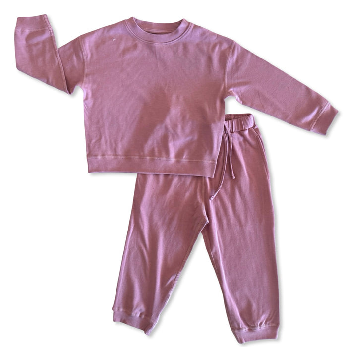 Pink sweatshirt and pants set on a white background