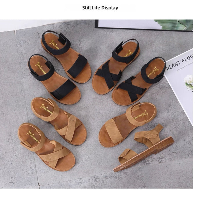Pair of brown sandals with black straps on a gray surface