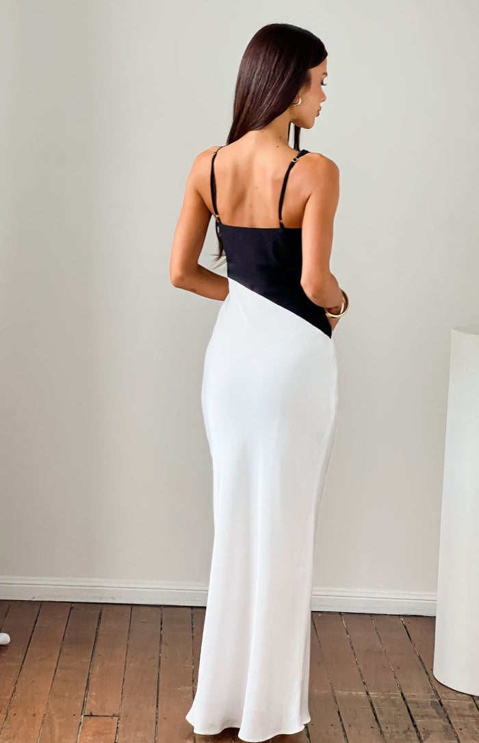 Rear view of a black and white satin maxi dress with thin adjustable spaghetti straps and a diagonal colour block design
