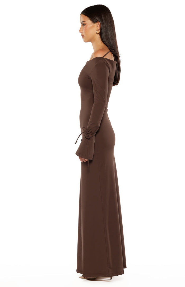 Side view of a chocolate jersey maxi dress with an off-shoulder neckline and long sleeves with tie cuffs