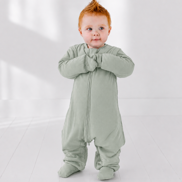 Baby wearing a light green onesie on a white background