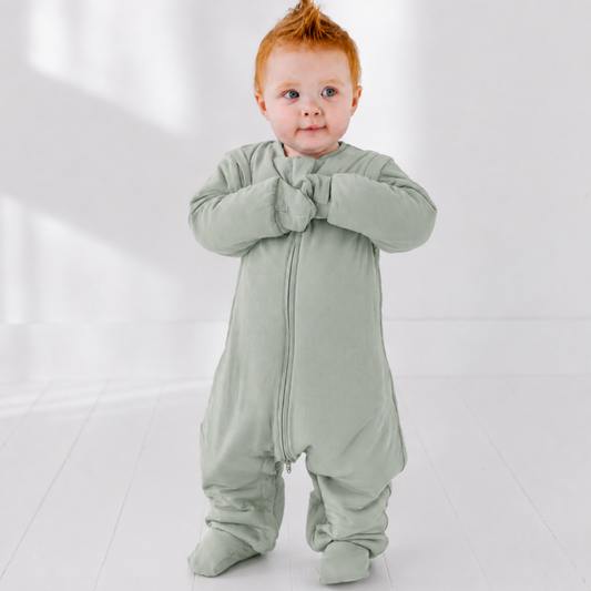 Baby wearing a light green onesie on a white background