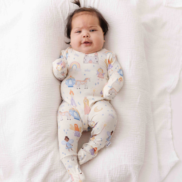 Baby wearing a colorful onesie lying on a white blanket