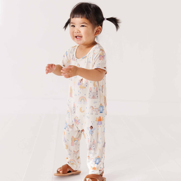 Child wearing a white onesie with colorful patterns on a plain background