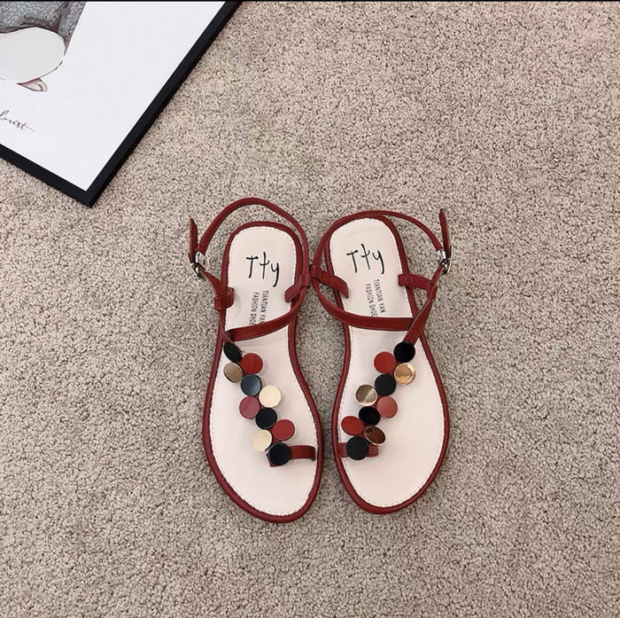 Pair of sandals with colorful pom-poms on a textured surface