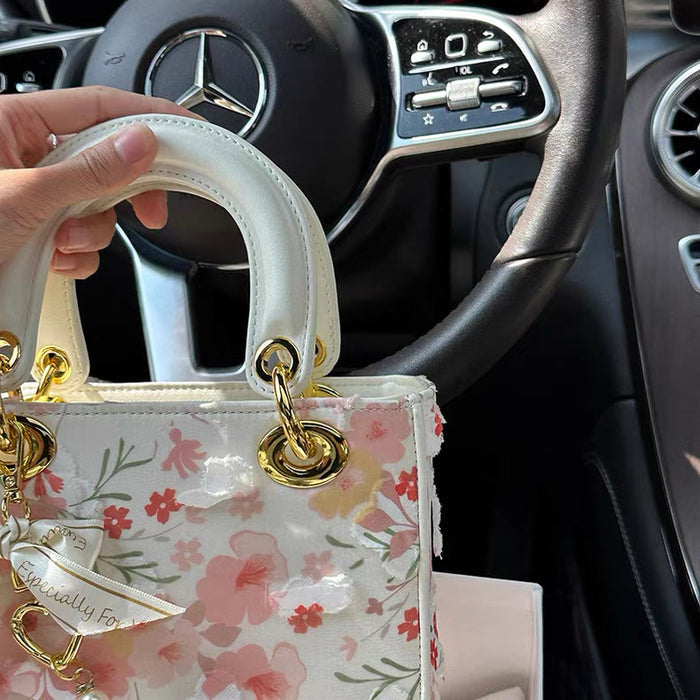 Floral handbag held in front of a Mercedes-Benz steering wheel