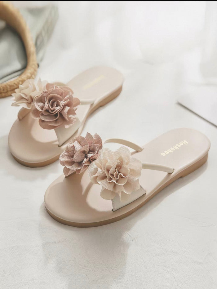 Beige sandals with floral decorations on a light background