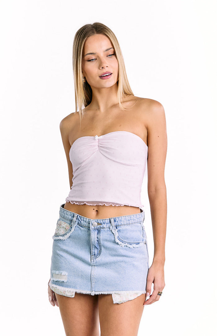 Front view of a light wash denim mini skirt with distressed details and floral fabric peeking through
