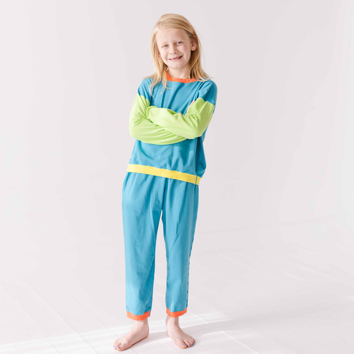 Young girl wearing a blue and green outfit with a yellow stripe on a white background