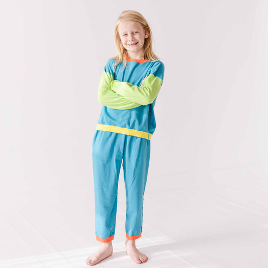 Young girl wearing a blue and green outfit with a yellow stripe on a white background