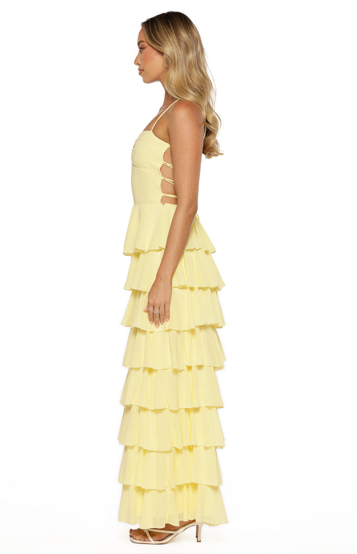 Side view of a yellow tiered ruffle maxi dress showing side cutouts with horizontal straps on the bodice