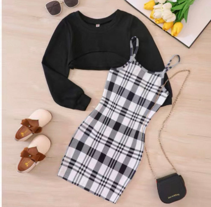 Black long-sleeve top, plaid dress, slippers, sunglasses, and a handbag on a wooden surface.