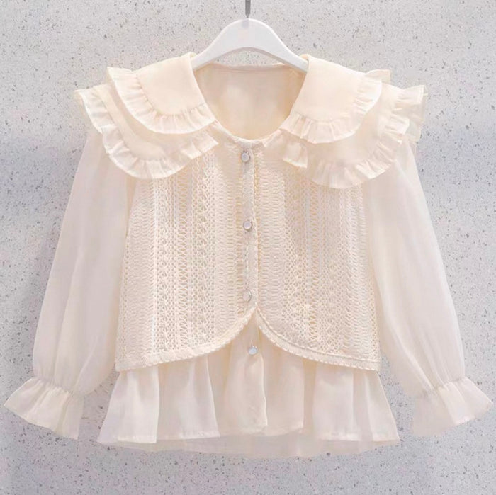 Cream-colored blouse with ruffled collar and cuffs on a hanger against a gray background