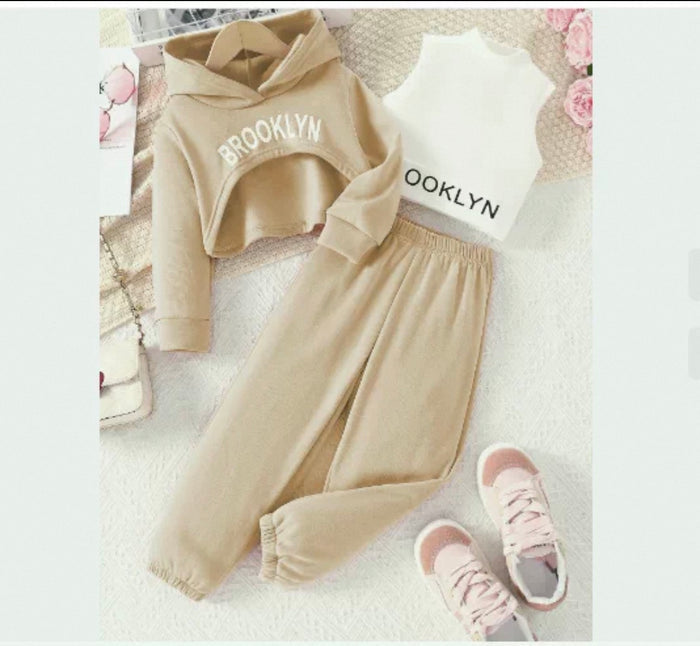 Children's beige hoodie, pants, and shoes with 'Brooklyn' text on a textured surface.