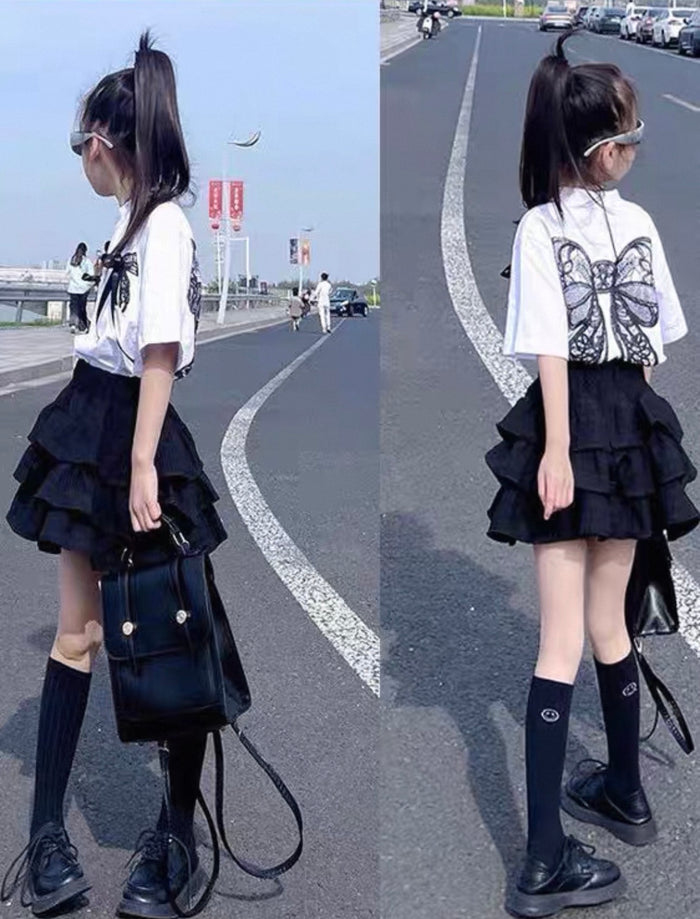 Young girl in a black and white outfit with a butterfly design on a road.