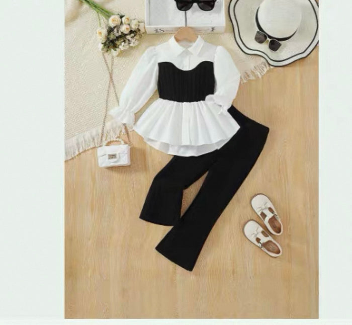 Black and white outfit with a blouse and pants on a wooden surface.