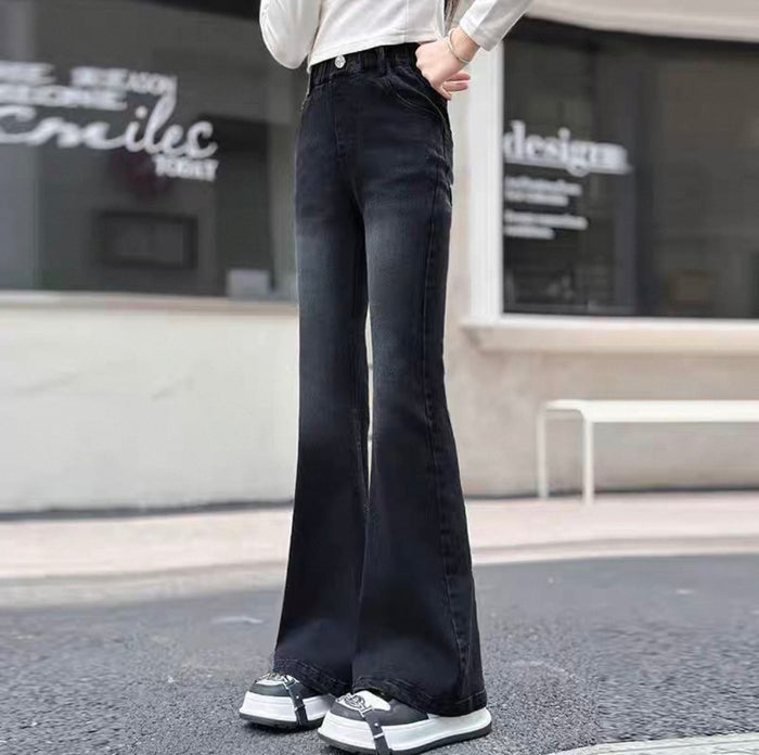 Person wearing black flared jeans standing on a street with a blurred background