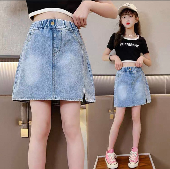 Two people wearing denim skirts with a neutral background
