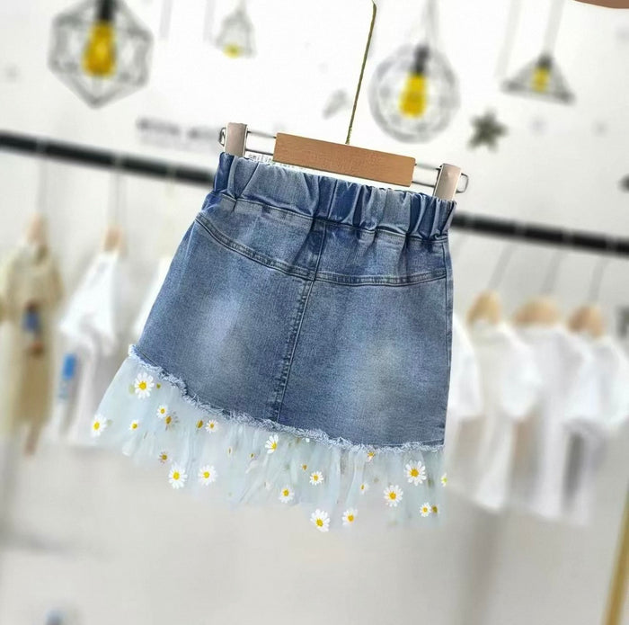 Denim skirt with floral hem on a hanger against a blurred background