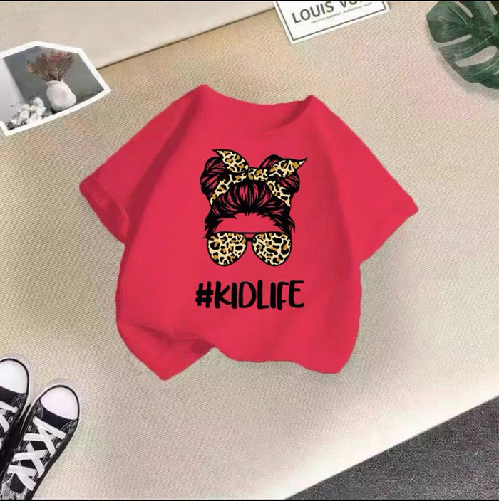 Red shirt with graphic design and '#KIDLIFE' text on a beige surface.