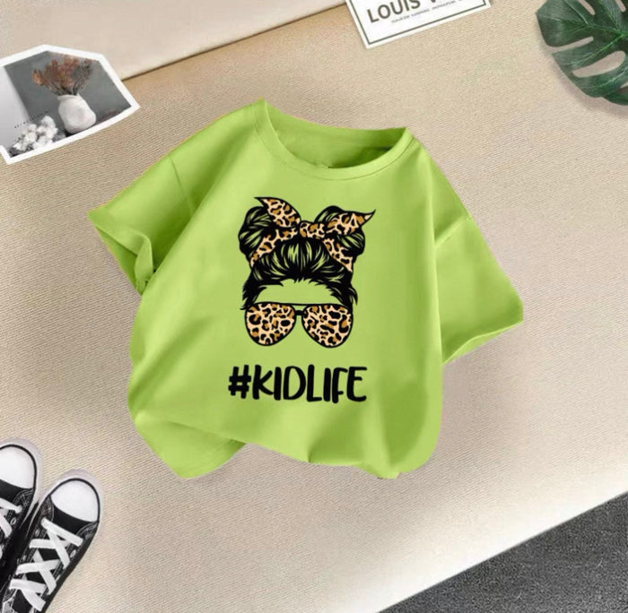 Green t-shirt with '#KIDLIFE' design on a beige surface