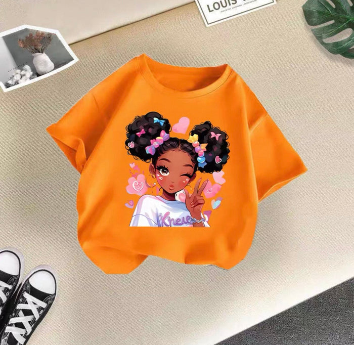 Orange t-shirt with a graphic of a girl with braids and flowers on a beige surface.