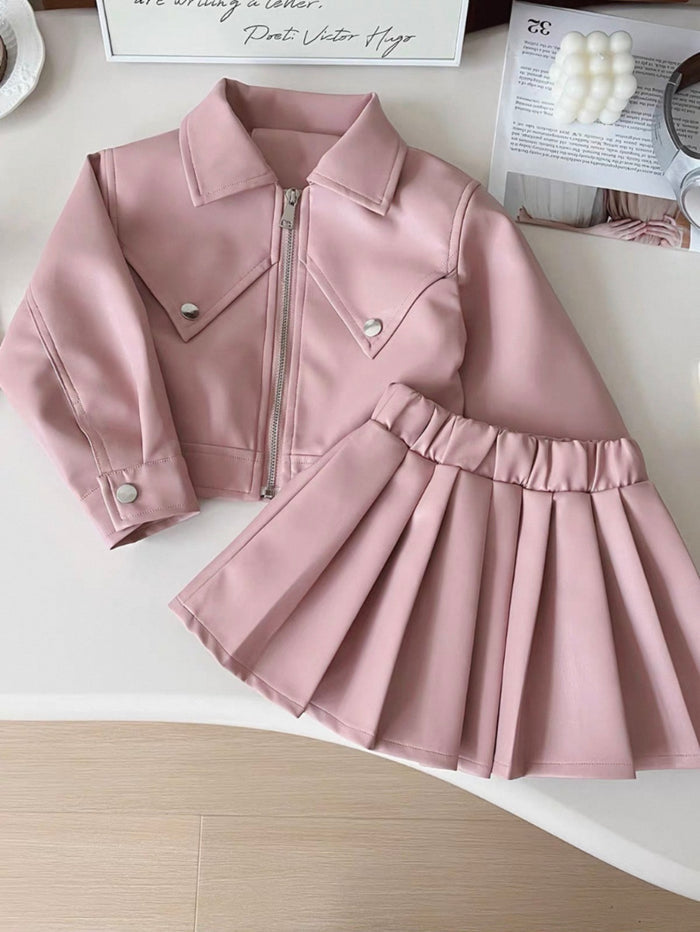 Pink jacket and skirt set on a white surface with a blurred background