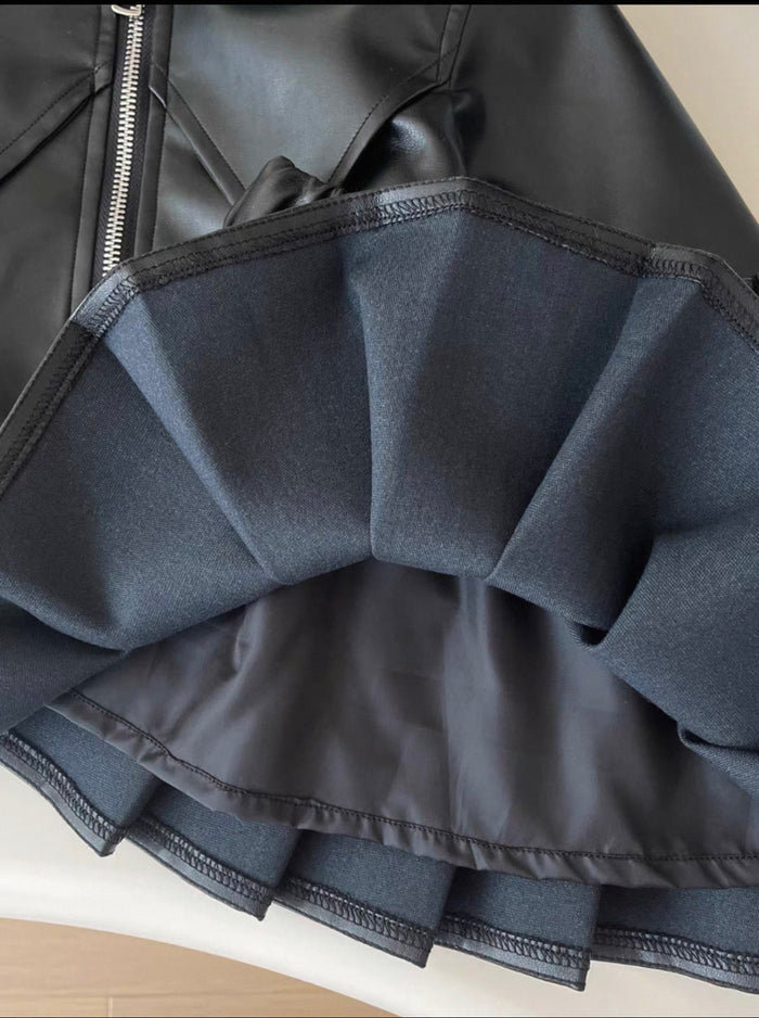 Close-up of a black leather skirt with ruffled hem on a light background