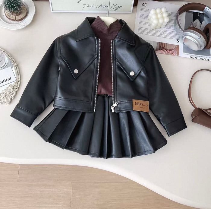 Black leather jacket with a pleated skirt on a white surface