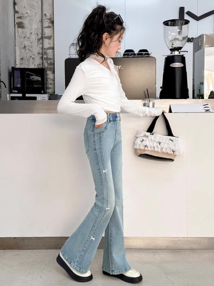 Person wearing light blue jeans and a white shirt in an office setting.