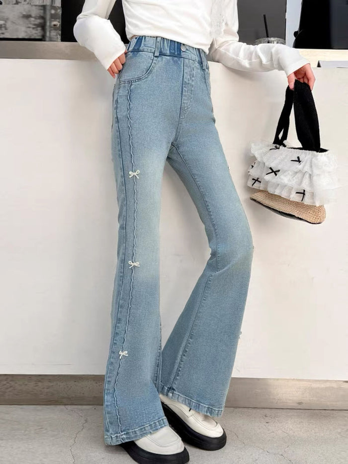Person wearing light blue flared jeans with a white background