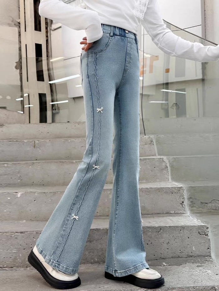 Person wearing light blue flared jeans standing on steps with a blurred background