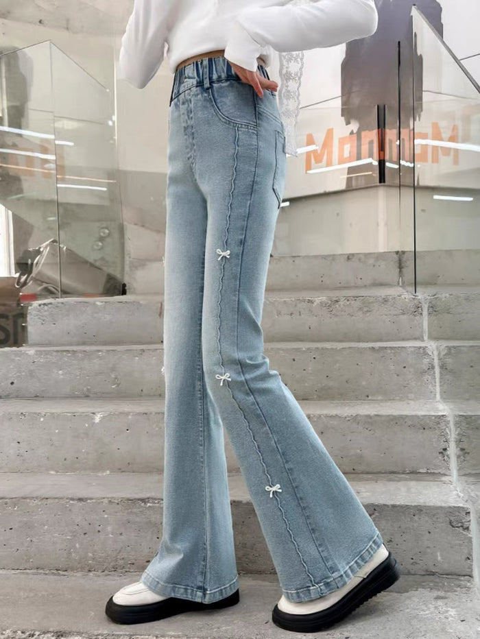 Person wearing light blue flared jeans and white sneakers on a concrete staircase.