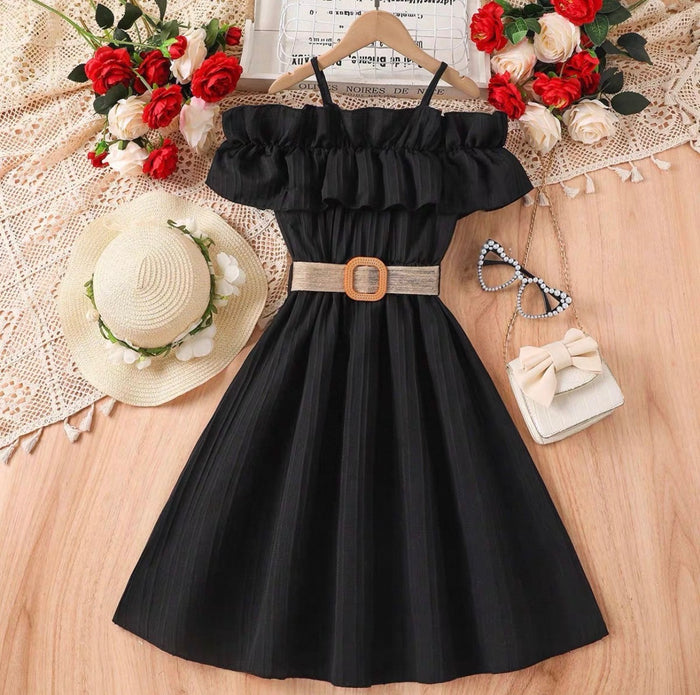 Black dress with a belt on a wooden surface with decorative items around