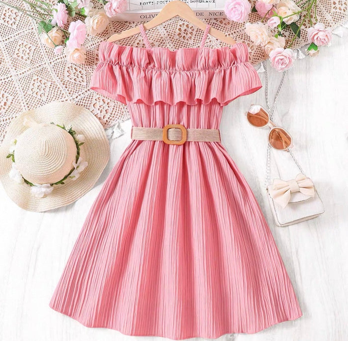 Pink dress with ruffled top and belt, surrounded by flowers and accessories on a white background