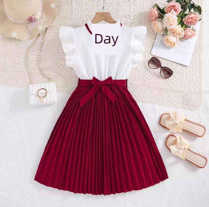 White top with 'Day' text and red pleated skirt on a white surface with accessories.
