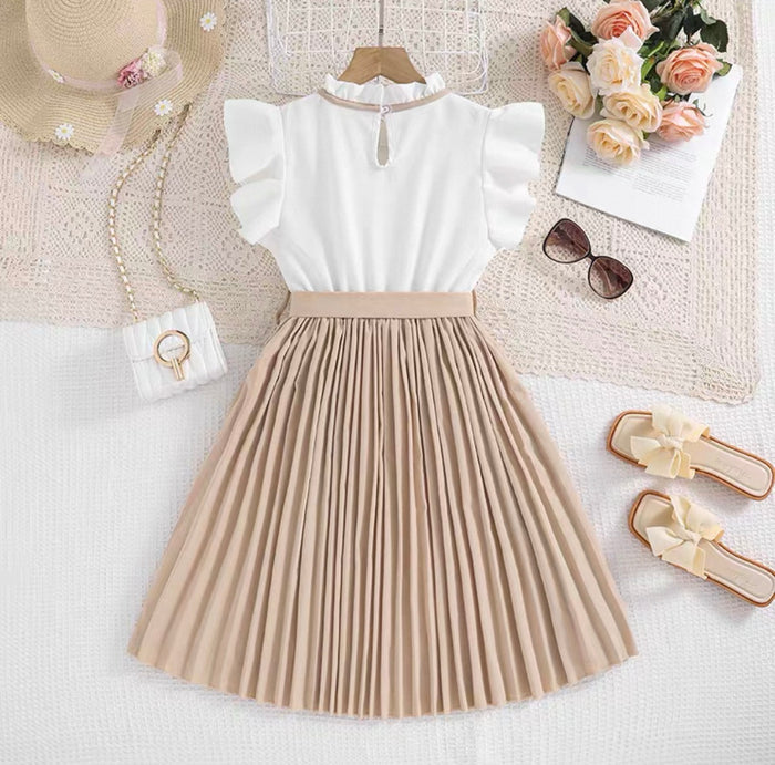 White top and beige pleated skirt with accessories on a light surface