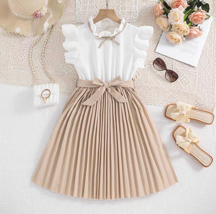 White blouse with beige pleated skirt on a white surface with accessories.