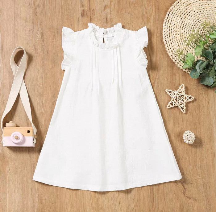 White dress on a wooden surface with decorative items around