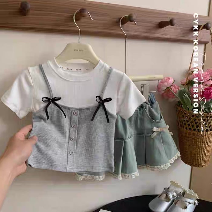 Children's outfit with a top and skirt on a hanger against a neutral background.