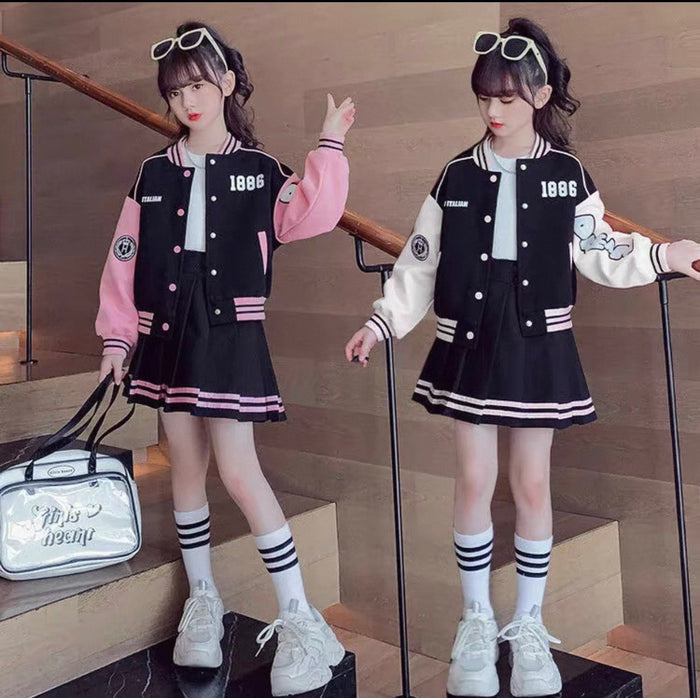 Two girls in matching black and white varsity jackets with pink and white accents, standing on a staircase.