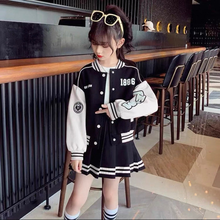 Person wearing a black and white varsity jacket with '1886' on it, standing in a restaurant.