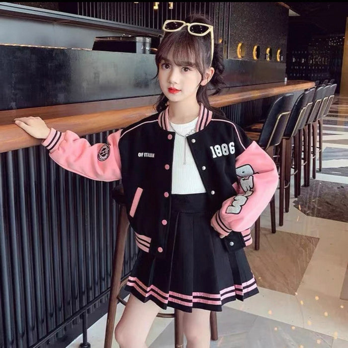 Person wearing a black and pink varsity jacket with cartoon character design in an indoor setting.