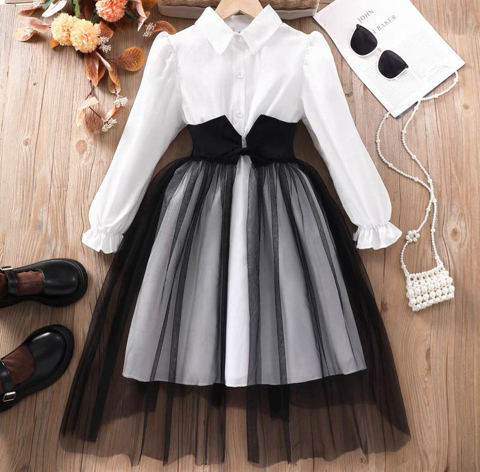 White blouse with black and gray tulle skirt on a wooden surface with accessories.