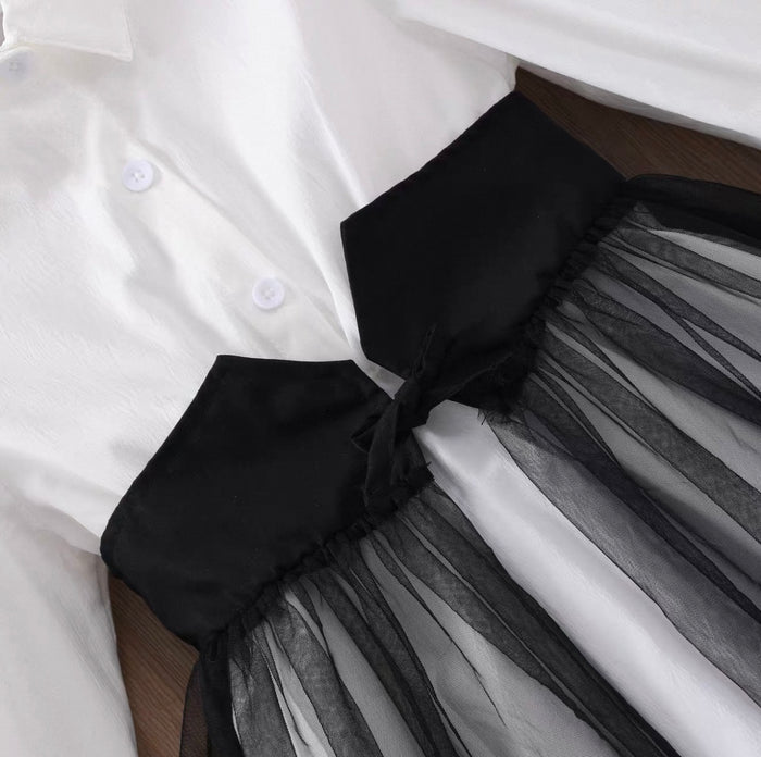 Close-up of a white shirt with a black bow and sheer black skirt.