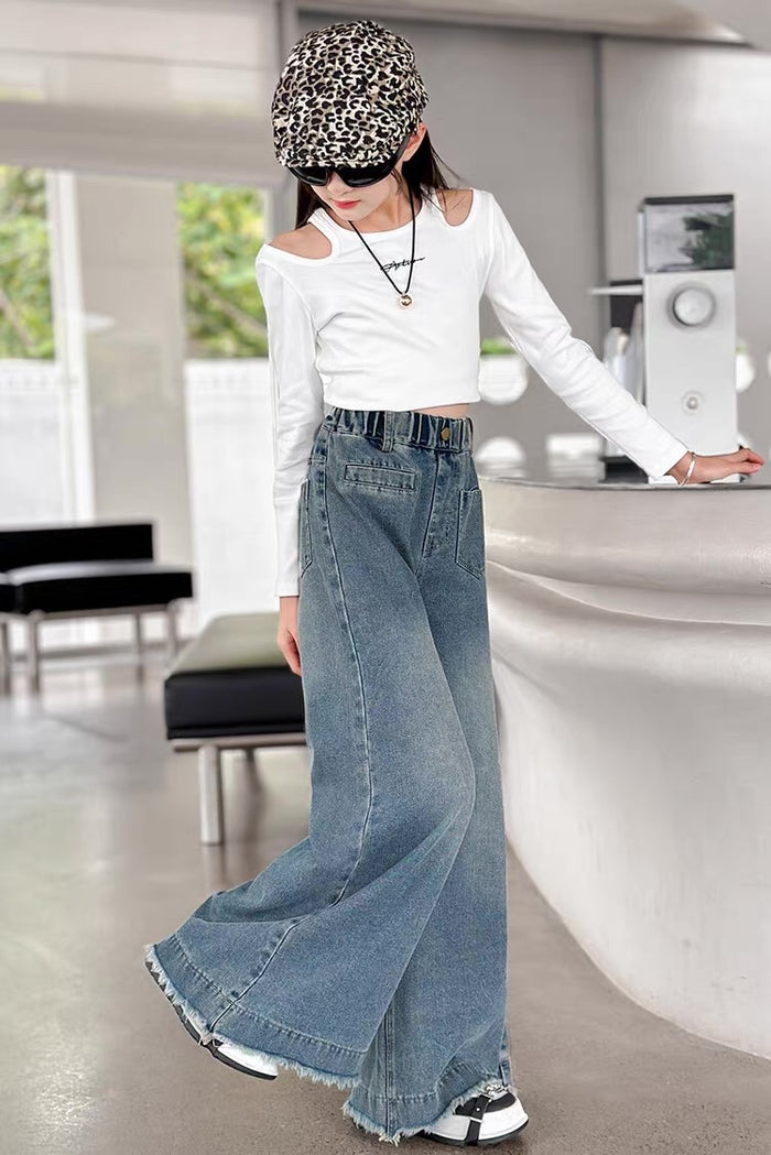 Person wearing a white off-shoulder top and blue jeans in an indoor setting.