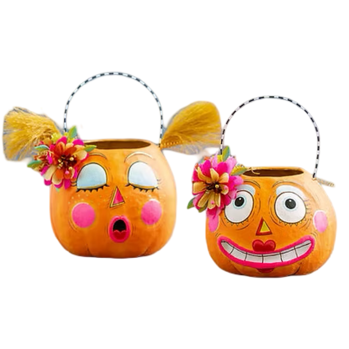 Two orange pumpkin-shaped bucket baskets with decorative faces and floral accents, shown on a plain white background. One has a surprised expression with closed eyes, and the other has a wide smiling expression with open eyes.
