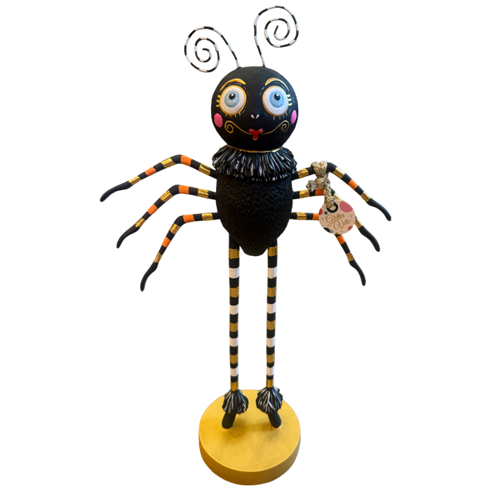Glitterville Spinderella black spider Halloween figure with oversized blue eyes, striped legs, ruffled collar, gold accents, and round gold base.