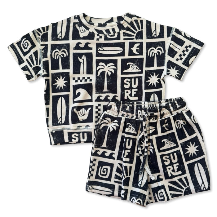 Children's t-shirt and shorts set with black and white surf-themed pattern on a white background