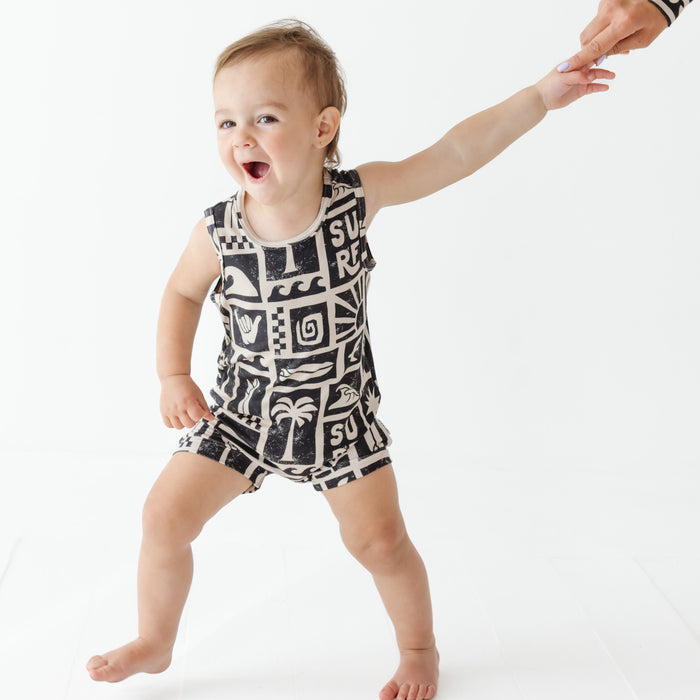 Child wearing a black and white patterned romper on a white background